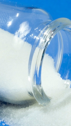 A flask of white superabsorbent powder poured onto a blue table cloth. A flask of white superabsorbent powder poured onto a blue table cloth.